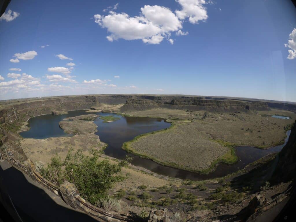 Overlooking Dry Falls Washington. Cliffsides ring the valley floor which is partially covered in water.