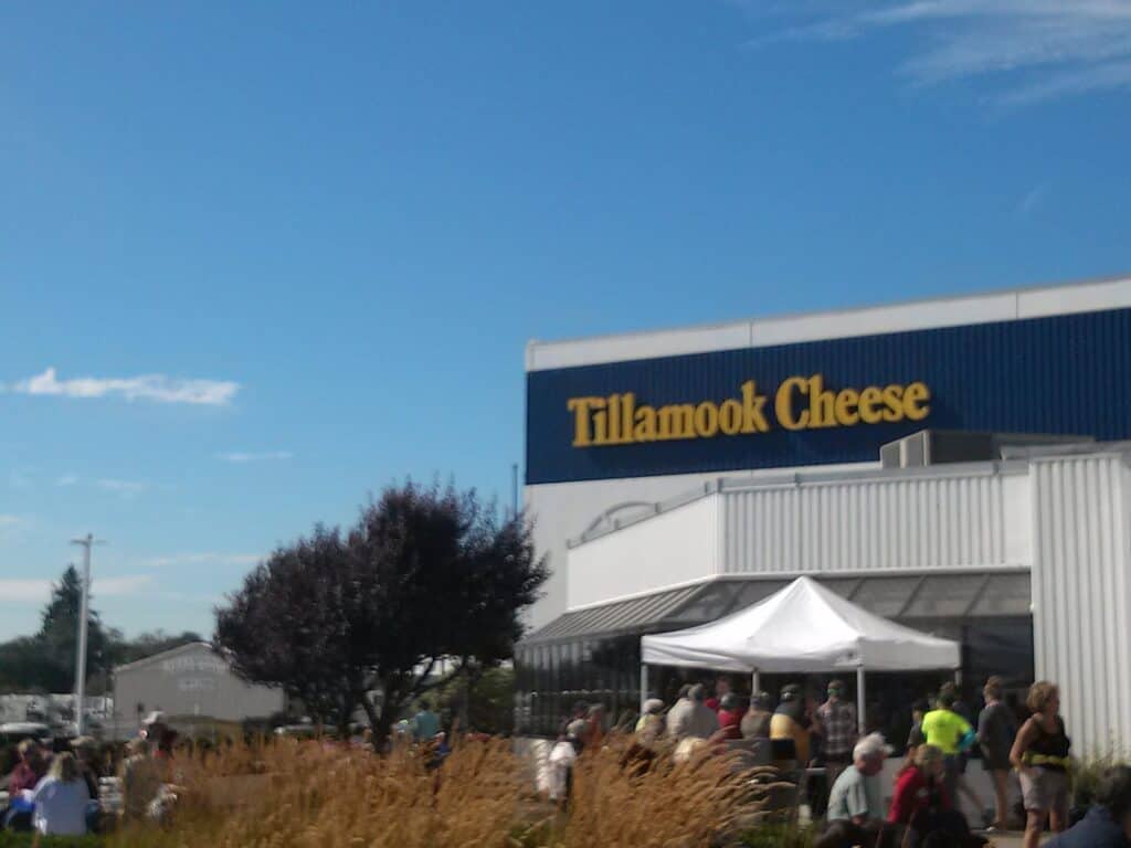 Tillamook Cheese Factory building and sign, with people milling about in front. Make this your main stop for a weekend in Tillamook Oregon.