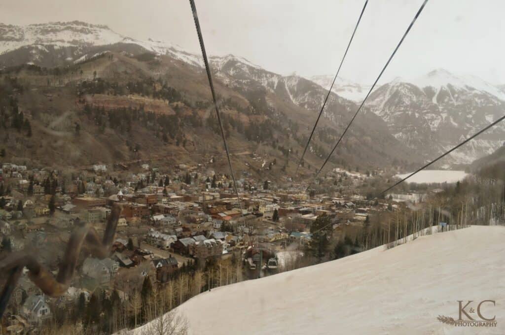 The Colorado mountain town of Telluride as seen from above in the gondola with the downtown framed by mountains covered in snow.