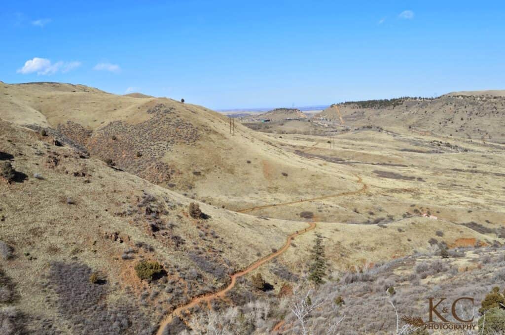 A winding dirt trail cuts through rolling golden hills in Matthews / Winters Park near Denver, Colorado. The wide-open landscape offers scenic views.