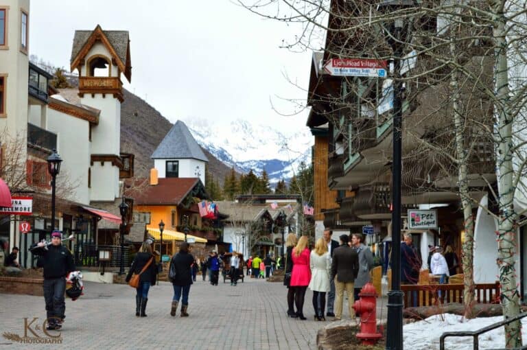 Vail Village pedestrian zone in winter with snow covered mountains in the background and many people walking about in this Colorado German mountain town.