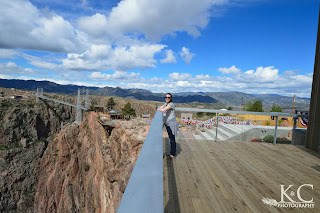 Woman overlooking the Royal Gorge Bridge & Park from the Visitor Center deck with the bridge in the distance.