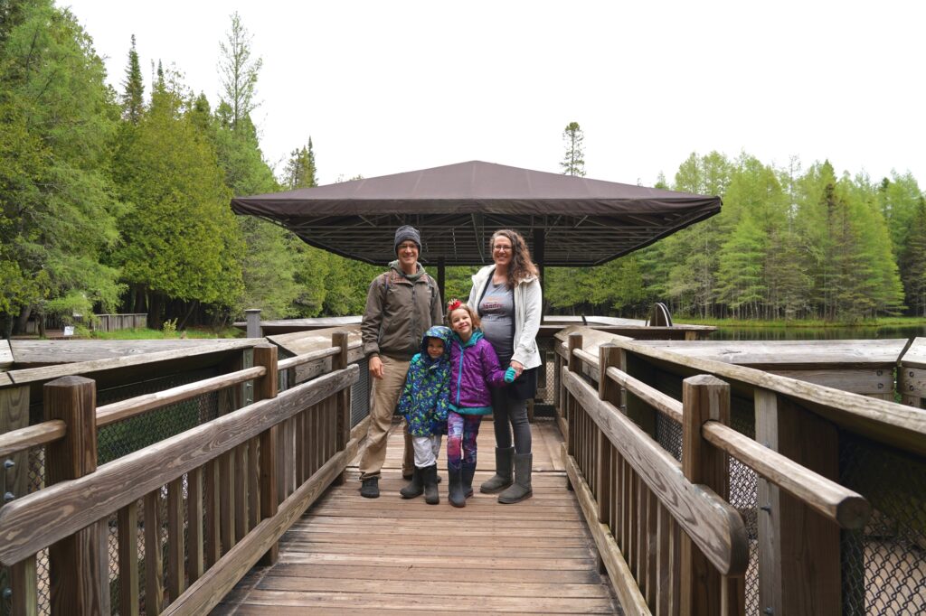 Family standing in front of the observation raft at Kitch-iti-kipi