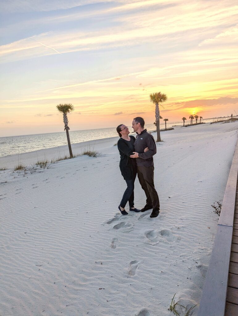 Couple on beach at sunset both wearing Kuhl travel pants