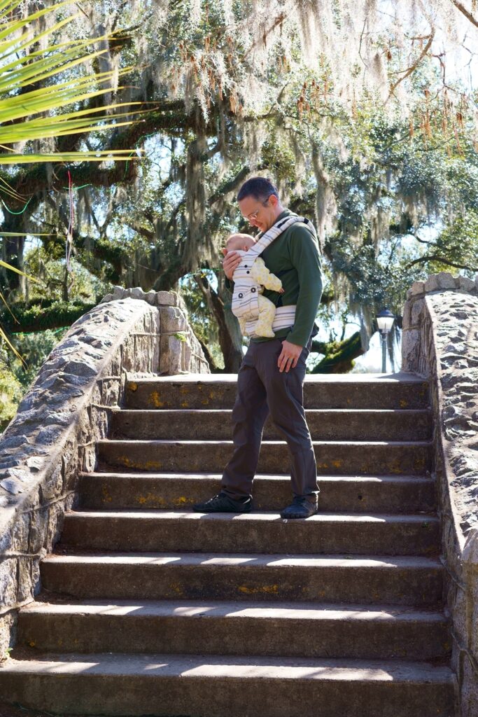 Man wearing baby in carrier on stairs