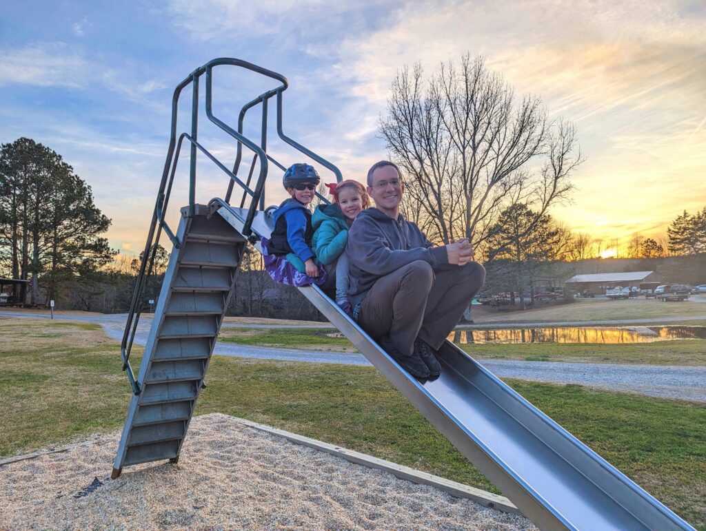 Man and kids going down playground slide